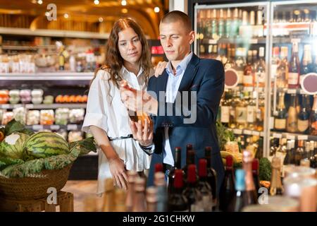 Couple choosing bottle of wine in supermarket Stock Photo