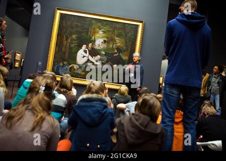 Le Déjeuner sur l'herbe by Manet, hanging in Musee D'Orsay and being studied by a large group of people Stock Photo