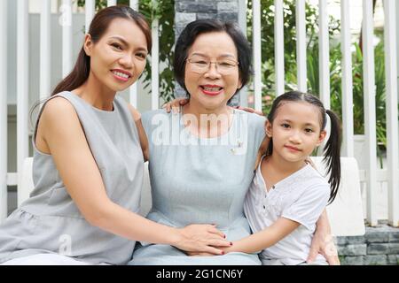 Portrait of happy senior woman enjoying spending time with daughter and granddaughter visiting her at home on birthday Stock Photo