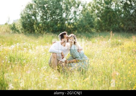 man hugs his beloved in meadow among wildflowers, concept of dating, falling in love Stock Photo