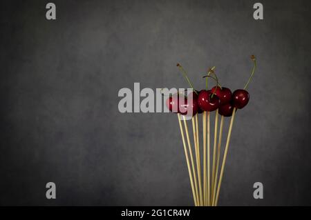 Cherries on skewer with grey background Stock Photo
