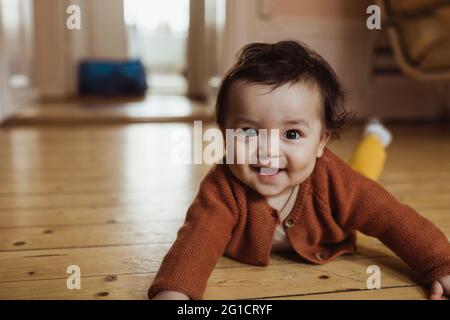 Portrait of smiling male toddler lying on floor at home Stock Photo