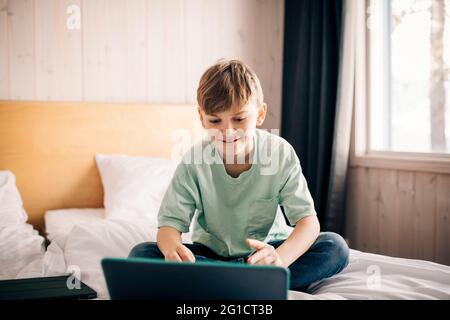 Blond boy E-learning through laptop at home Stock Photo