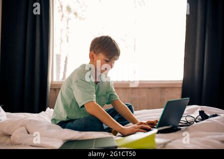 Boy using laptop while doing homework in bedroom Stock Photo