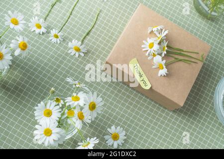 Gift decorated with chamomile flowers with words of gratitude. top view flat lay, eco friendly and zero waste packaging. High quality photo Stock Photo