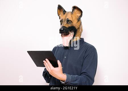 person with a dog mask using a digital tablet on white background, concept of technology and communication Stock Photo