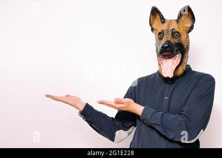 person with a dog mask showing with hands what's on the side on white background, copy space for text Stock Photo