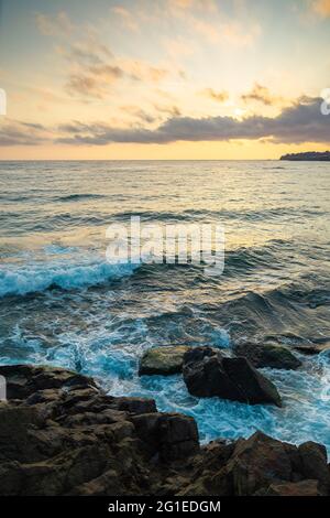 landscape at the sea. beautiful nature background in autumn at sunrise. clouds on the sky above horizon in morning light. water waves crashing coastli Stock Photo