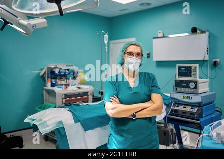 Self assured female doctor in medical uniform looking at camera with folded arms in hospital Stock Photo