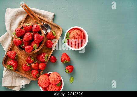 Strawberry sorbet with strawberries on blue background with copy space. Heap of strawberry with cups of ice cream. Stock Photo