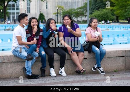 A family, likely South Americnas, enjoy ice creams near the Unisphere in Flushing Meadows Corona Park in Queens, New York City Stock Photo