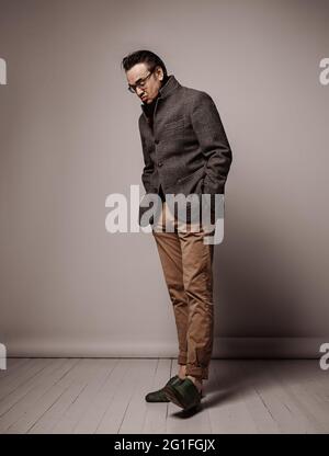 Portrait of snobby intellectual adult man in checkered jacket and black scarf looking down at his shoe sole Stock Photo