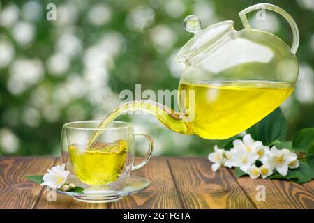 teapot pouring tea into flying cups, on white background Stock