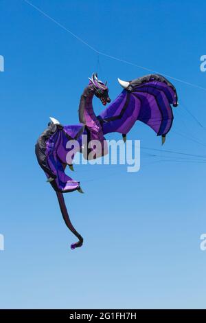 Dragon kite flying in the air against blue sky at Poole, Dorset UK in May Stock Photo