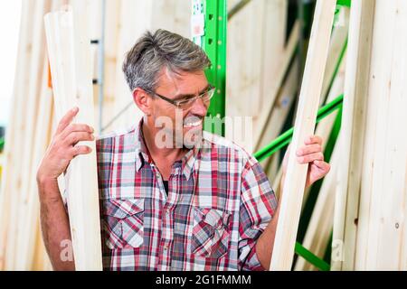 Customer in lumber department of hardware store choosing wood strip for DIY-project Stock Photo