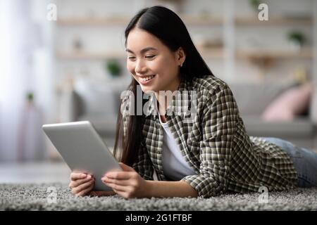 Positive asian woman surfing on social media, using digital tablet Stock Photo