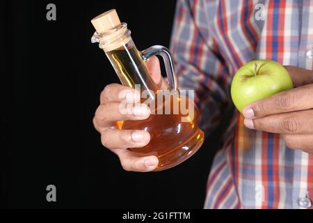 hand holding apple vinegar in glass bottle with fresh green apple  Stock Photo