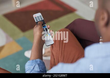 Close up of African-American man holding TV remote and switching channels, copy space Stock Photo