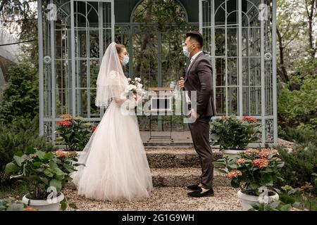 side view of bride and groom near laptop with blank screen in alcove in park Stock Photo