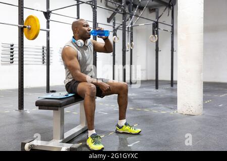 African American man hydrating after exercise in fitness center. Space for text. Stock Photo