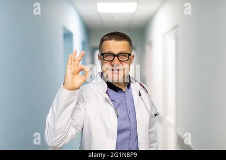 Happy male doctor is showing ok sign. Making circle with fingers. Gesture of approval. Stock Photo