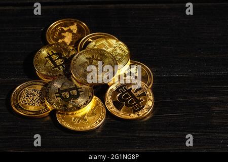 Closeup golden coin with bitcoin logo. Leader in cryptocurrency Bitcoin BTC on a top of coins against black wooden surface. Pile of decentralized Stock Photo
