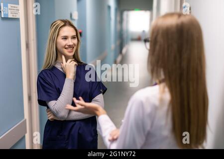Two woman doctor with mask talking in hospital corridor, health care. female doctors examining a file in a bright office. People teamwork healthy and Stock Photo