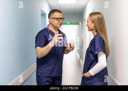 Two doctors discussing diagnosis while walking Stock Photo