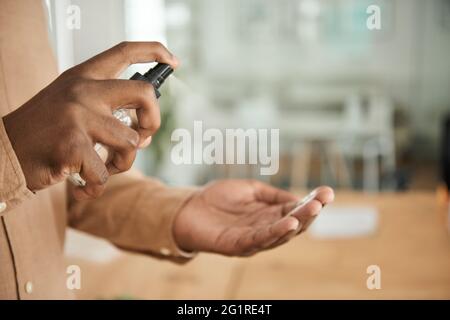 African businessman using hand sanitizer in an office Stock Photo