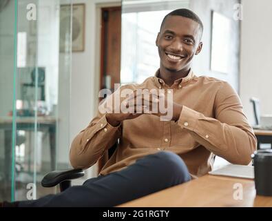 Smiling young African businessman sitting at his office desk Stock Photo