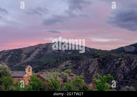 village among mountains at sunset with church and bell tower as foreground in La Vereda in Guadalajara in Spain