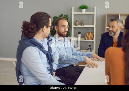 Young company manager or business mentor talking to diverse workers in office meeting Stock Photo