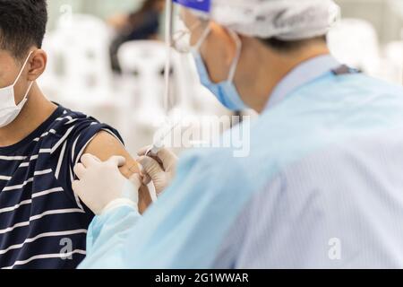 Doctor in protective suit giving patient a vaccine for coronavirus disease. Stock Photo