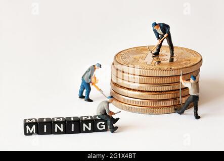 Group of miner figurines with equipment working on stack of bitcoins near black cubes with MINING text. Stock Photo
