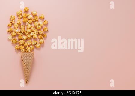 popcorn with caramel in a waffle cone on a pink background top view. Stock Photo