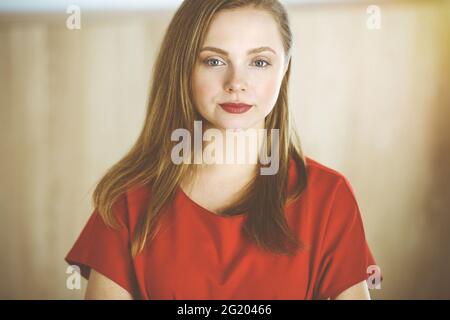 Head shot of a smart confident smiling millennial european woman standing with folded arms at home Stock Photo