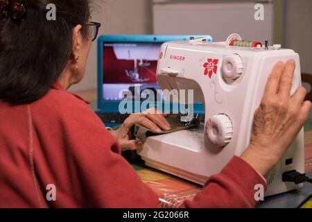 SANTA MARIA CAPUA VETERE, ITALY - Feb 08, 2021: Caserta, Italy, February 08th 2021, Grandma taking a video tutorial on how to learn to use the sewing Stock Photo