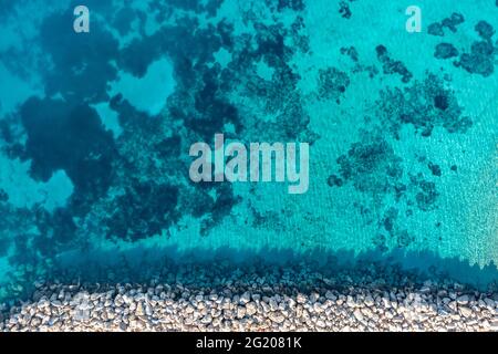 Breakwater and turquoise blue color sea background, aerial drone top down view. Rocky protection wall on clear rippled water, Cyclades Koufonisi islan Stock Photo