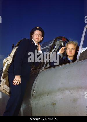 Women's Air Force Service Pilot Anne McClellan adjusts her earphones in the cockpit of a BT-13 while Ann Johnson stands on the wing of the plane, no location, circa 1944.  (Photo by US Army Air Force/RBM Vintage Images) Stock Photo