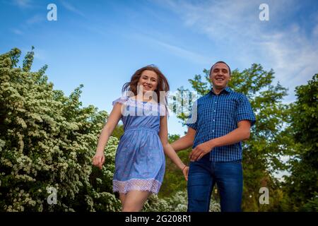 Couple running in spring blooming park. Young man and woman having fun at sunset. Stock Photo