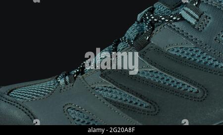 Closeup to the upper part of a blue gray fabric and leather sports shoe on a black background Stock Photo