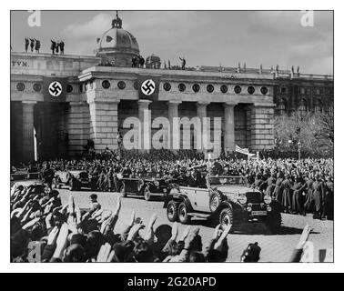 Anschluss Hitler Vienna Occupation German Chancellor Adolf Hitler (1889 - 1945) is Heil Hitler saluted by ecstatic crowds as he drives past in 6 wheel all terrain open Mercedes to a troop parade ceremony with swastika banners flags in Nazi occupation Vienna, Austria, 15th March 1938. Stock Photo