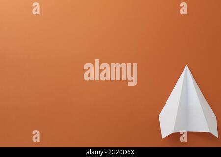 Paper white plane on orange background. Close-up Stock Photo