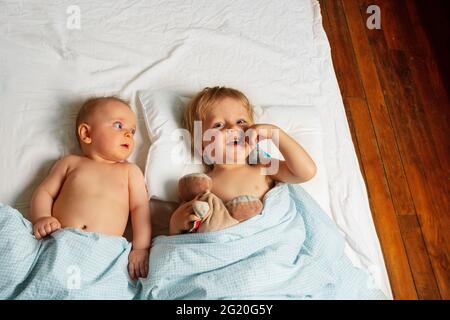 Little kids, boy and girl lay in a bed waking up Stock Photo