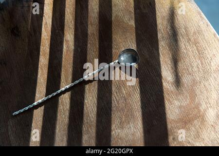 long teaspoon with twist handle for ice cream, yoghurt and desserts to eat in striped shade on a wooden chair. Concept Stock Photo