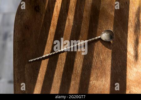 long teaspoon with twist handle for ice cream, yoghurt and desserts to eat in striped shade on a wooden chair. Concept Stock Photo
