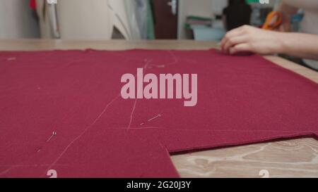 Image of seamstress cutting pattern on fabric in workshop Stock Photo