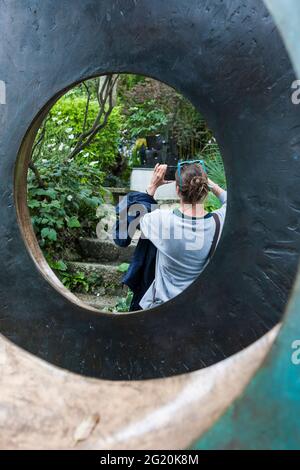 A glimpse through 'Four-Square (Walk Through)' (1966), of another photographer: Barbara Hepworth Sculpture Garden, St. Ives, Cornwall.  MODEL RELEASED Stock Photo