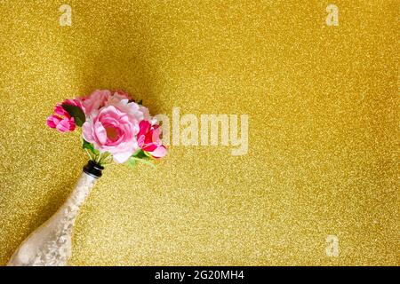 bouquet of flowers in a bottle of champagne. glitter gold background, creative minimal party composition, celebration, place for text Stock Photo