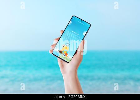 Travel app on smart phone display in woman hand concept. Summer vacation plan concept. Sea in background Stock Photo